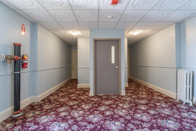 carpeted empty room featuring baseboards and radiator heating unit