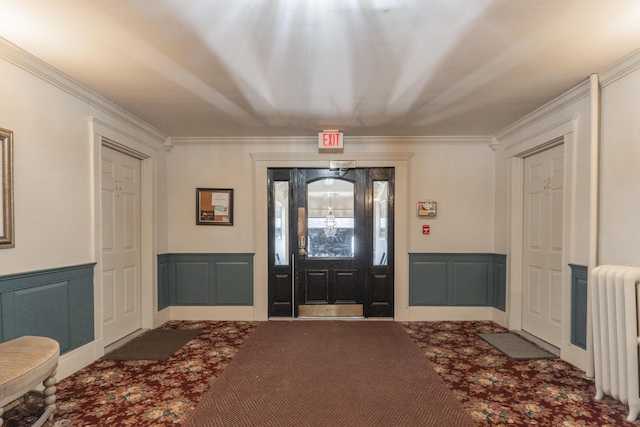 carpeted foyer with ornamental molding, radiator heating unit, and a decorative wall