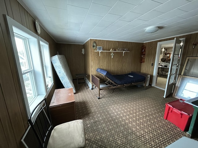 carpeted bedroom with wooden walls and crown molding