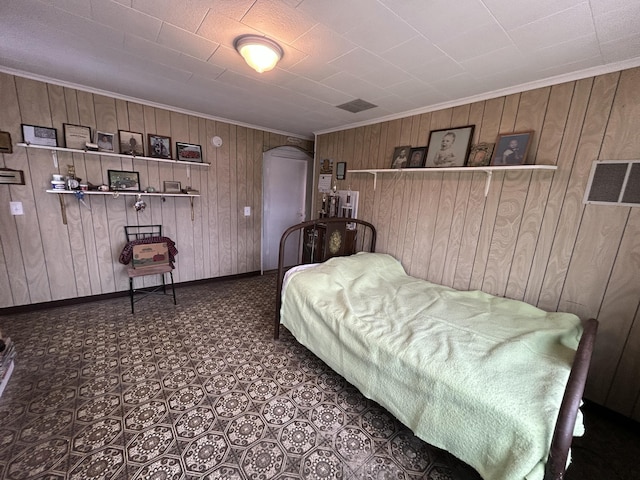 bedroom featuring arched walkways, ornamental molding, wood walls, and baseboards