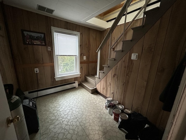 doorway featuring visible vents, a baseboard radiator, stairway, light floors, and wood walls