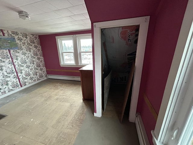 interior space with a baseboard heating unit, baseboards, and wallpapered walls