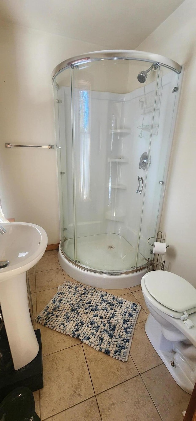 full bathroom featuring toilet, tile patterned flooring, and a shower stall