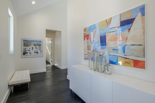 hall featuring high vaulted ceiling, baseboards, dark wood-style flooring, and recessed lighting