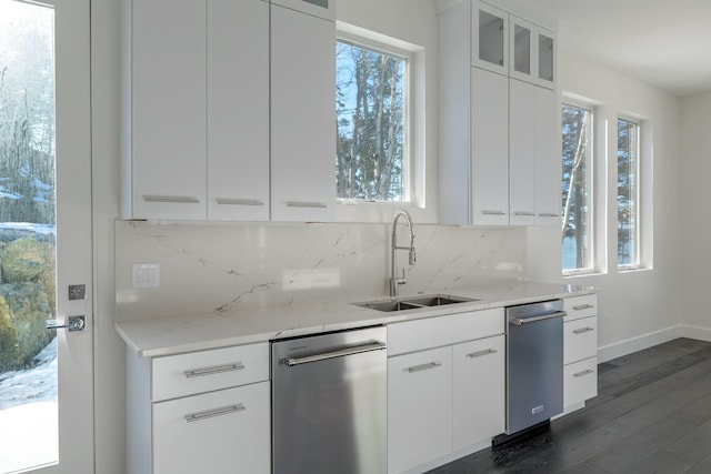 kitchen with dark wood finished floors, dishwasher, glass insert cabinets, a sink, and backsplash