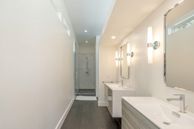 full bath featuring a stall shower, baseboards, a sink, and wood finished floors