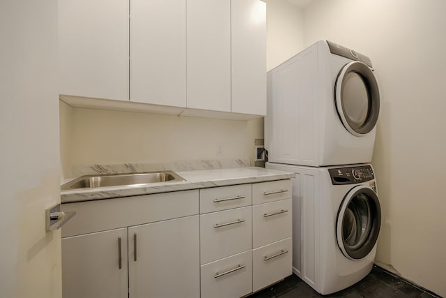 laundry room with stacked washer / dryer, cabinet space, and a sink