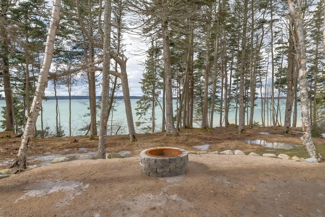 view of yard with an outdoor fire pit and a water view