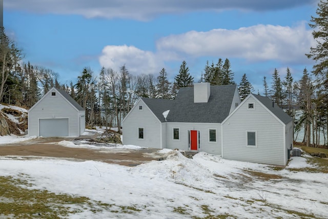 view of front of home featuring central air condition unit, a detached garage, a chimney, and an outbuilding