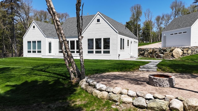 101 Cow Pt, Roque Bluffs, ME 04654 - rear view of house with an outdoor fire pit, roof with shingles, and a lawn