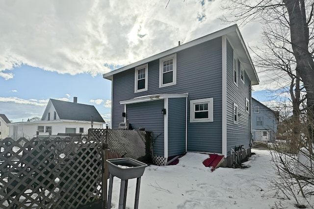 snow covered rear of property featuring fence