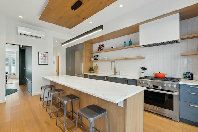 kitchen with a wall mounted AC, modern cabinets, open shelves, and high end stainless steel range