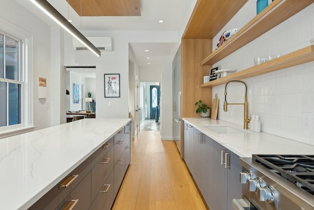 kitchen featuring a wall unit AC, a sink, light wood-style floors, gray cabinets, and modern cabinets