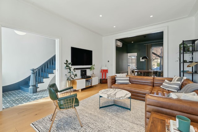 living area with stairs, ornamental molding, wood finished floors, and a wall mounted air conditioner