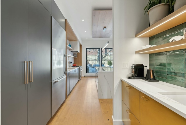 kitchen with open shelves, tasteful backsplash, light wood-style floors, modern cabinets, and stainless steel built in refrigerator