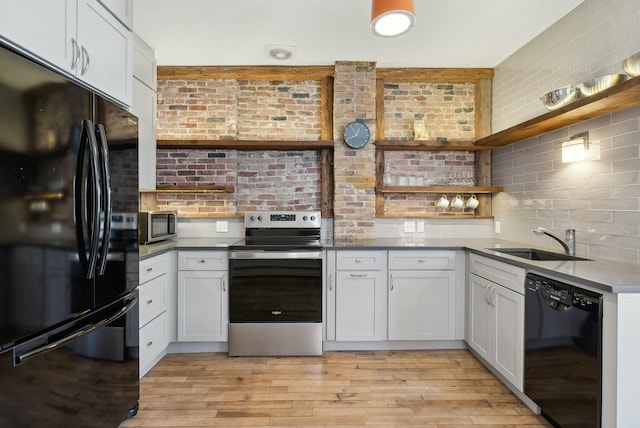 kitchen with light wood-style flooring, open shelves, a sink, decorative backsplash, and black appliances