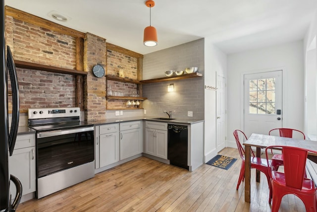 kitchen with light wood-style flooring, open shelves, a sink, black appliances, and dark countertops