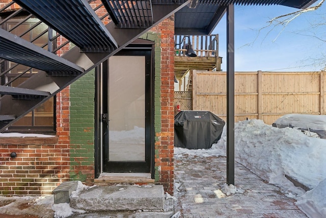 doorway to property featuring brick siding and fence