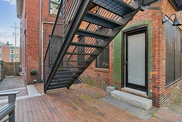 doorway to property featuring brick siding, fence, a gate, and a pergola