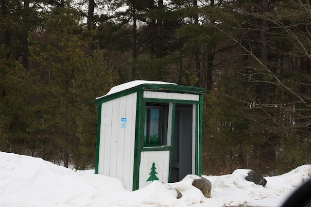 snow covered structure with an outbuilding and a shed