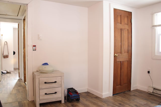 hall with attic access, baseboards, dark wood-style flooring, and baseboard heating