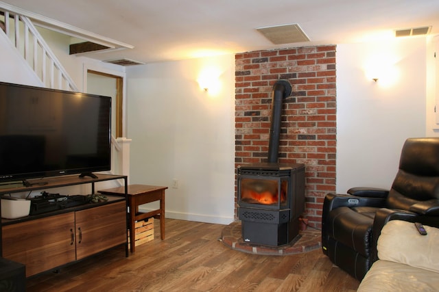 living area featuring visible vents, baseboards, wood finished floors, and a wood stove