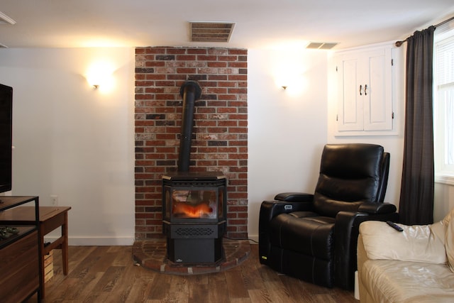 living area with visible vents, baseboards, dark wood-type flooring, and a wood stove