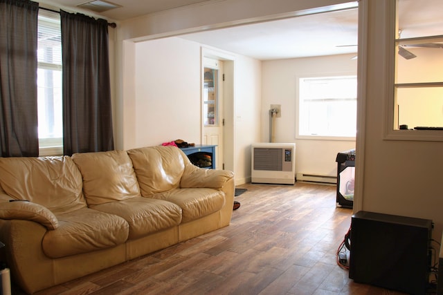 living room with a baseboard heating unit, wood finished floors, and visible vents