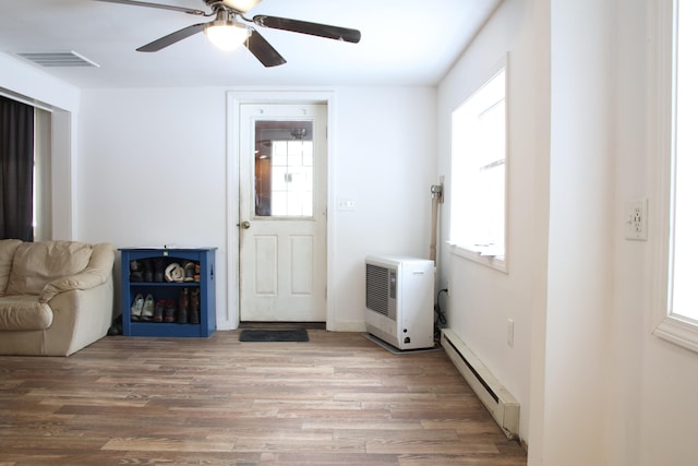 interior space featuring a healthy amount of sunlight, light wood-style floors, visible vents, and a baseboard radiator