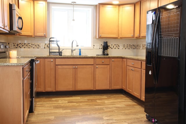 kitchen featuring a sink, stainless steel appliances, tasteful backsplash, and light wood-style flooring