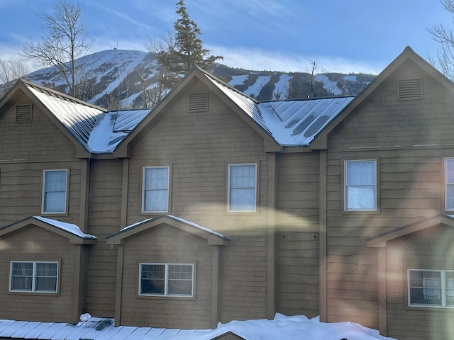 snow covered house featuring a mountain view, metal roof, and a standing seam roof