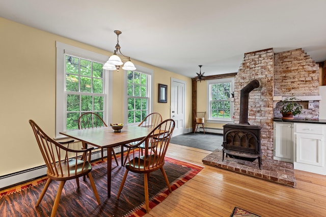 323 Runaround Pond Rd, Durham, ME 04222 - dining area featuring a baseboard heating unit, a wood stove, and hardwood / wood-style floors