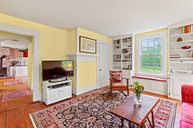 323 Runaround Pond Rd, Durham, ME 04222 - living area featuring hardwood / wood-style flooring, built in shelves, a wood stove, and arched walkways