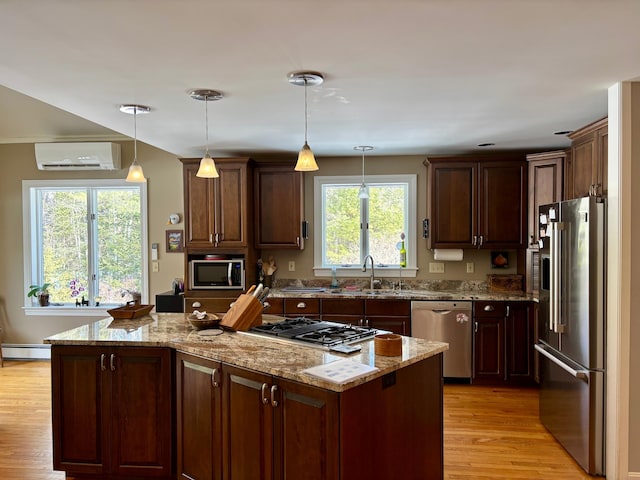 kitchen with a wall unit AC, light wood finished floors, a baseboard radiator, appliances with stainless steel finishes, and a center island