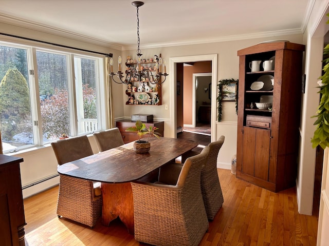 dining area with a baseboard heating unit, a notable chandelier, ornamental molding, and light wood finished floors