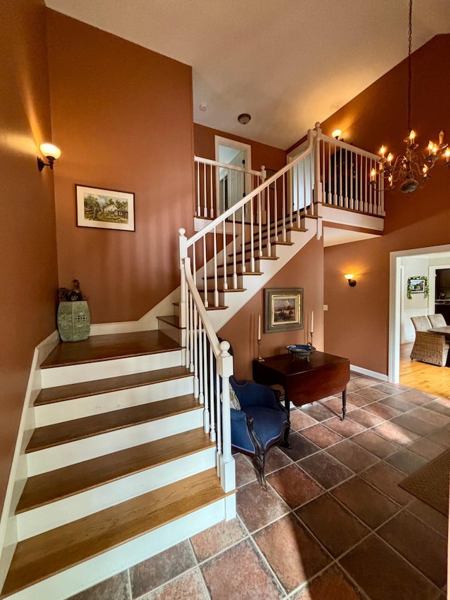 stairs with an inviting chandelier, baseboards, and a towering ceiling