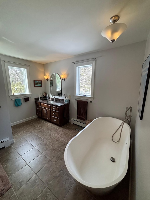 bathroom featuring a baseboard heating unit, a soaking tub, plenty of natural light, and double vanity