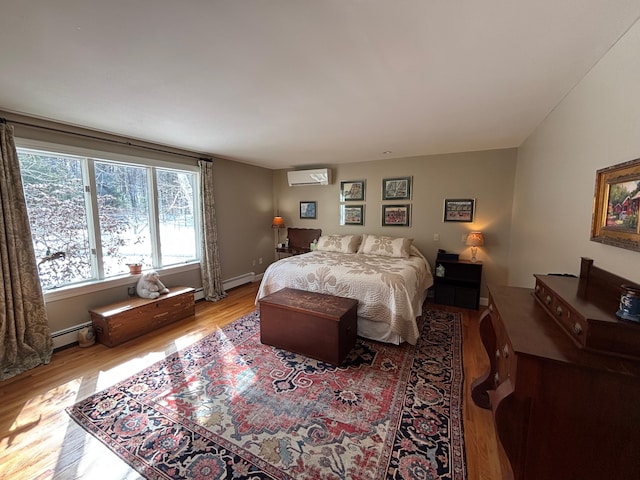 bedroom with a baseboard radiator, baseboards, a wall unit AC, and wood finished floors