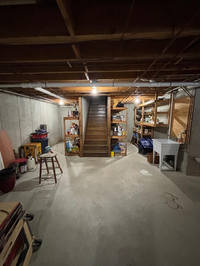 unfinished basement featuring stairway and a sink