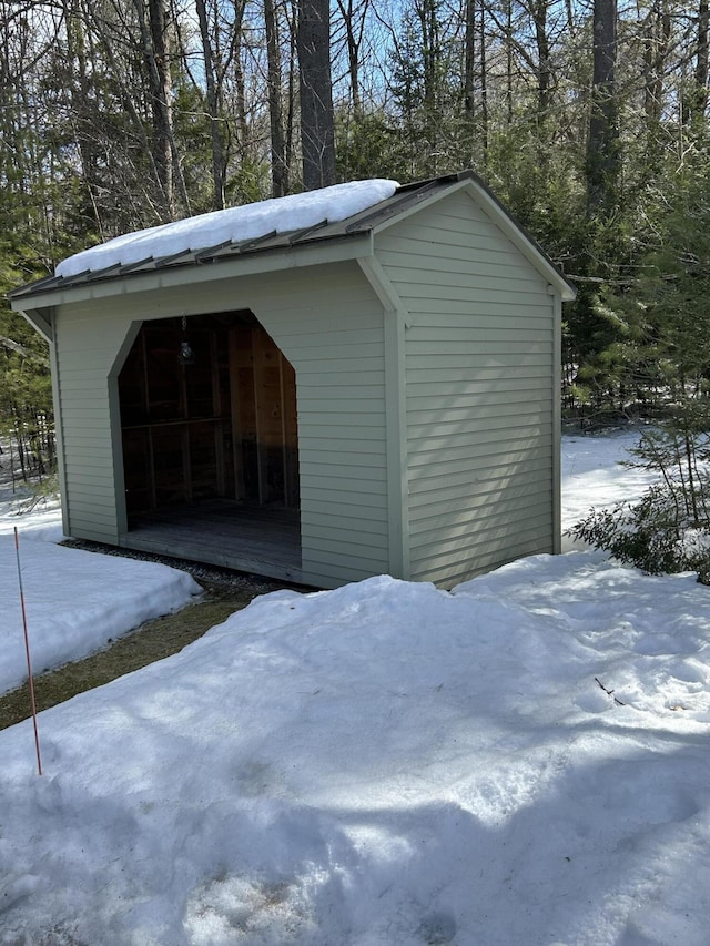 snow covered structure featuring an outbuilding