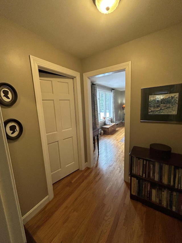 hallway featuring baseboards and wood finished floors