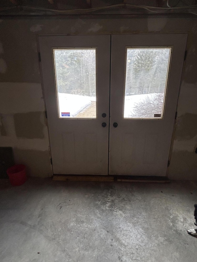 doorway to outside featuring french doors, plenty of natural light, and unfinished concrete floors