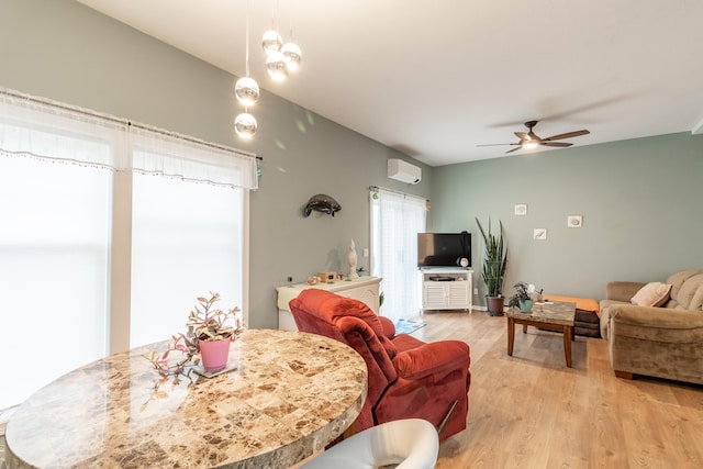 living area with a wall mounted air conditioner, ceiling fan, and light wood finished floors