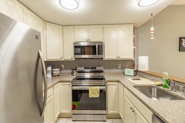 kitchen featuring a textured ceiling, stainless steel appliances, light tile patterned flooring, and a sink