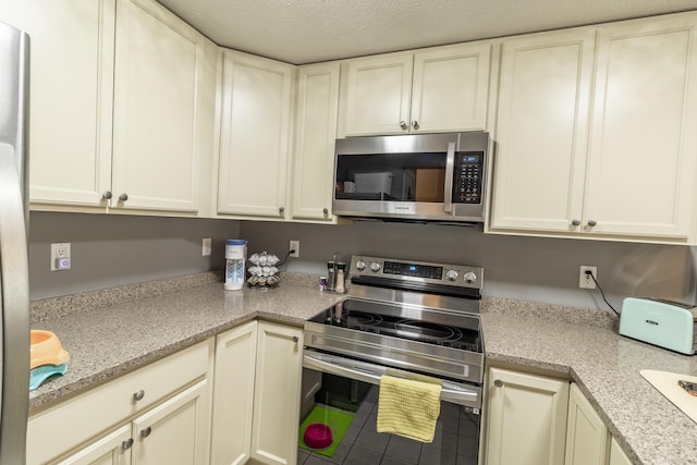 kitchen featuring light stone countertops, white cabinetry, appliances with stainless steel finishes, and a textured ceiling