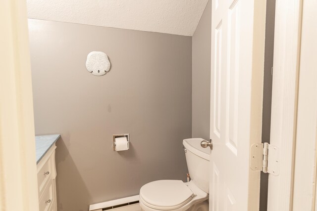 bathroom featuring toilet, vanity, baseboard heating, and a textured ceiling