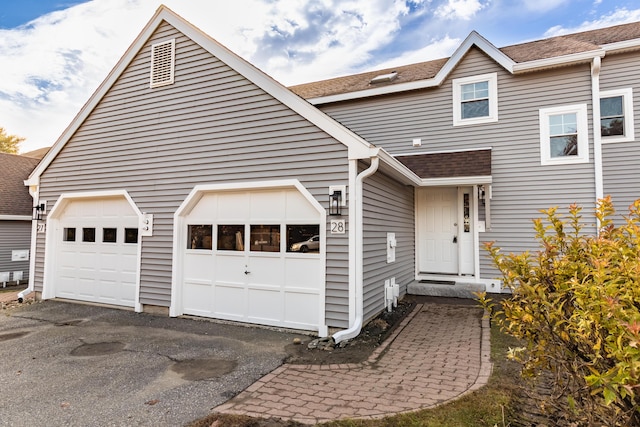 view of front of property with driveway, an attached garage, and roof with shingles