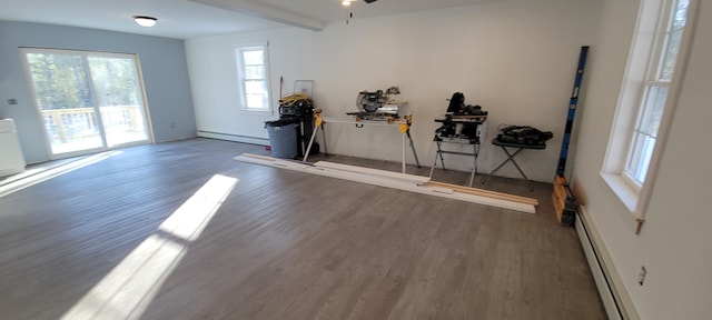 workout room with wood finished floors, a ceiling fan, and a baseboard radiator