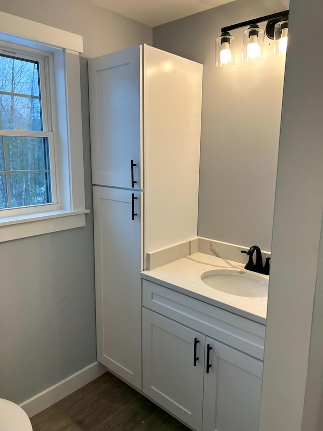 half bathroom featuring vanity, wood finished floors, and baseboards