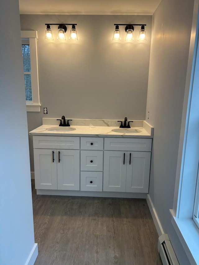 full bath with a sink, wood finished floors, baseboards, and a baseboard radiator